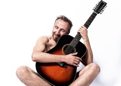 Helmut Sanftenschneider sitzend mit Gitarre